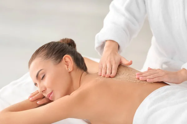 Jonge vrouw ondergaat een behandeling met bodyscrub in de spa salon — Stockfoto