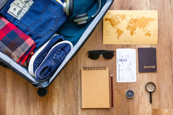 Maleta con ropa y accesorios masculinos, pasaporte, entradas y mapas sobre fondo de madera —  Fotos de Stock