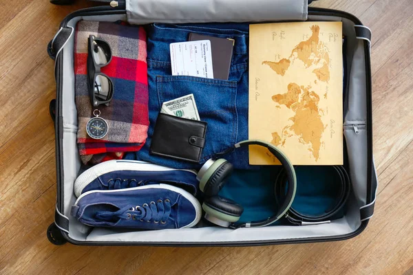 Suitcase with male clothes, accessories and map on wooden background — Stock Photo, Image