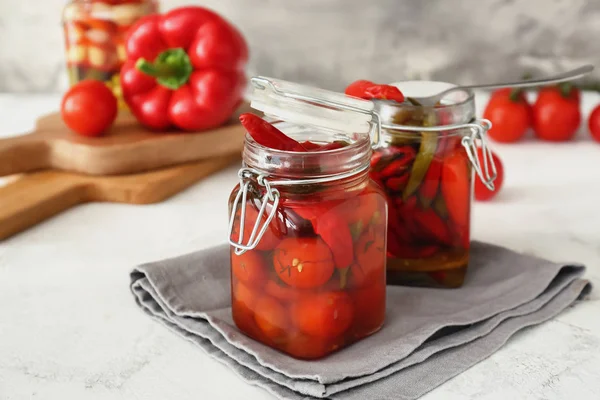 Frascos com tomates enlatados e pimenta na mesa — Fotografia de Stock