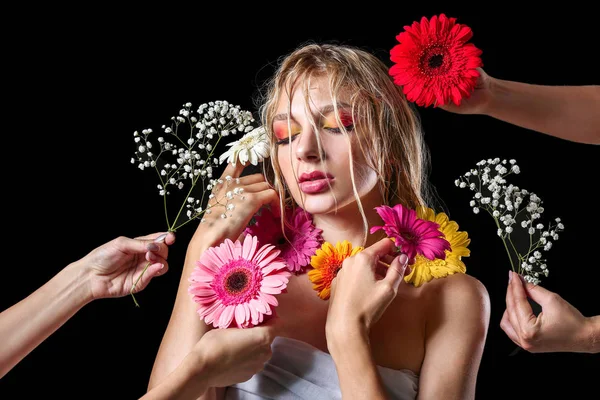 Piękna seksowna młoda kobieta i ręce z kwiatami na ciemnym tle — Zdjęcie stockowe
