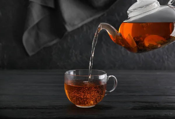 Pouring of hot tea into cup on table — Stock Photo, Image