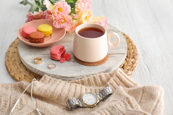 Xícara de chá quente, flores e macarons na mesa — Fotografia de Stock