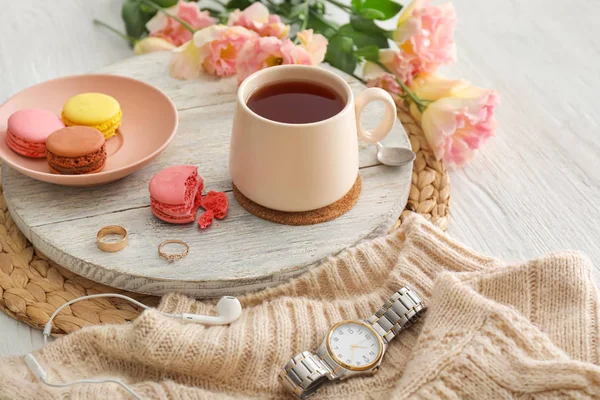 Xícara de chá quente, flores e macarons na mesa — Fotografia de Stock