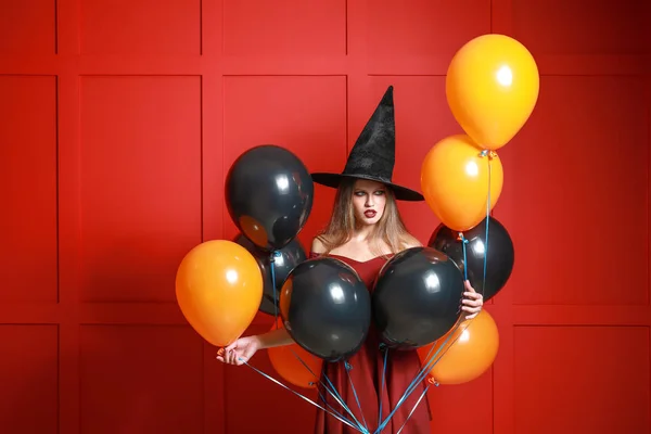 Mooie vrouw verkleed als heks voor Halloween op kleur achtergrond — Stockfoto