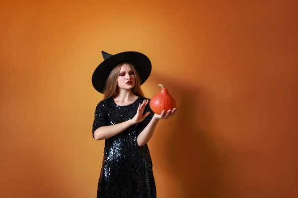 Красивая женщина, одетая как ведьма на Хэллоуин на цветном фоне — стоковое фото