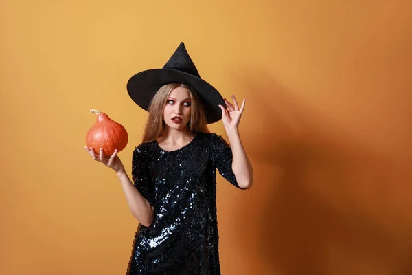 Mooie vrouw verkleed als heks voor Halloween op kleur achtergrond — Stockfoto