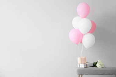 Hafif arka plan karşı bankta hediye kutuları ve çiçekler ile Hava balonları