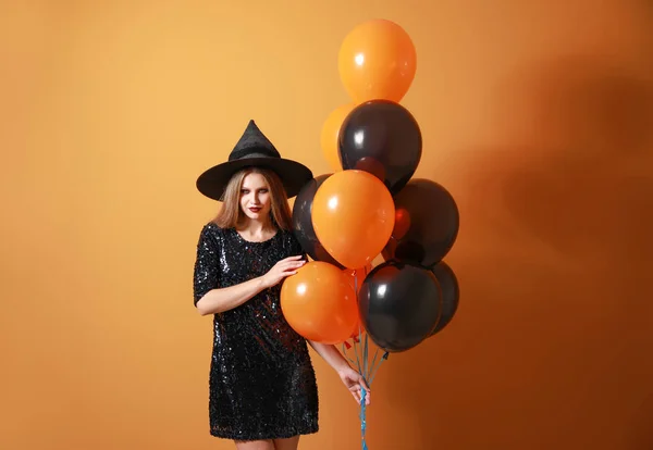 Mooie vrouw verkleed als heks voor Halloween op kleur achtergrond — Stockfoto