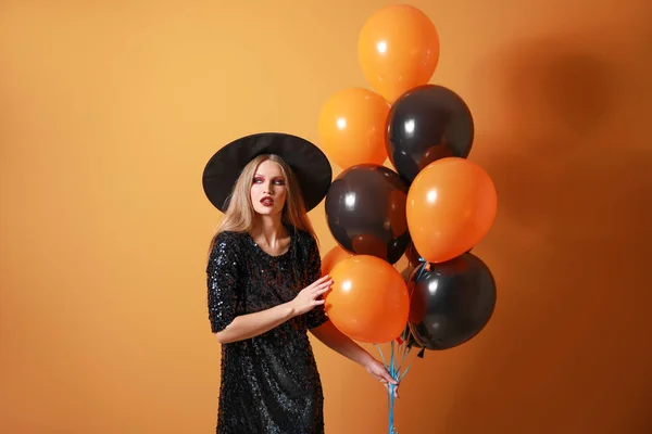 Beautiful woman dressed as witch for Halloween on color background — Stock Photo, Image