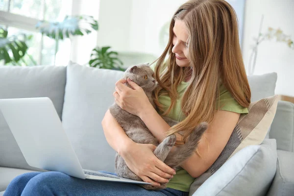 Mulher bonita com gato bonito e laptop sentado no sofá em casa — Fotografia de Stock