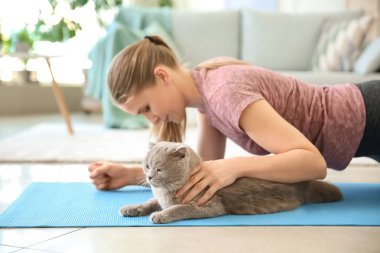 Sevimli kedi ile güzel kadın evde yoga yapıyor