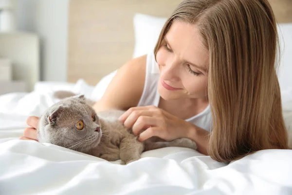 Красива жінка з милою кішкою лежить в ліжку вдома — стокове фото