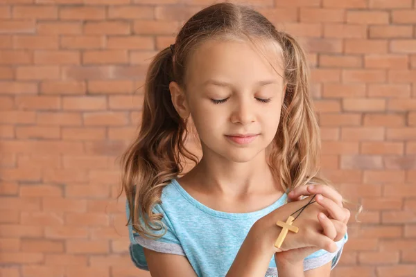 Cute little girl praying against brick wall — Stock Photo, Image