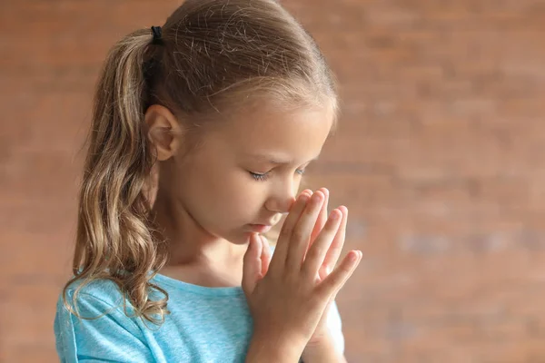 Cute little girl praying against blurred background — Stock Photo, Image