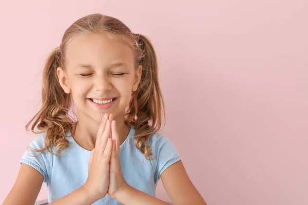 Praying little girl on color background — Stock Photo, Image