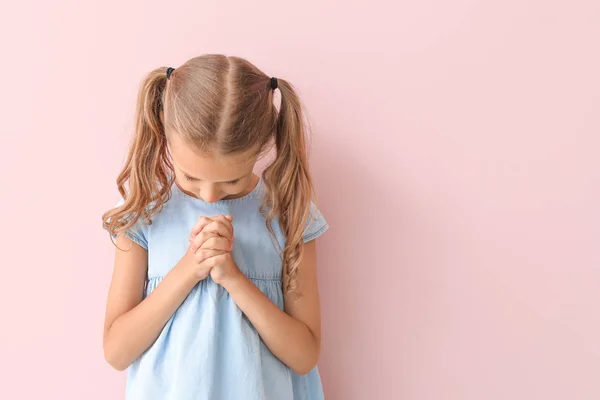 Praying little girl on color background — Stock Photo, Image