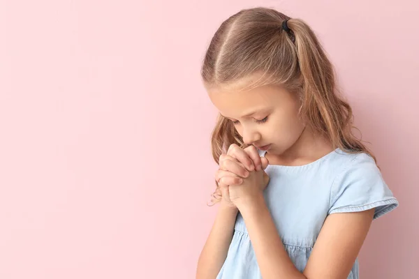 Praying little girl on color background — Stock Photo, Image