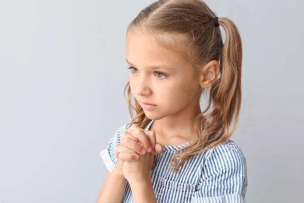 Praying little girl on light background — Stock Photo, Image