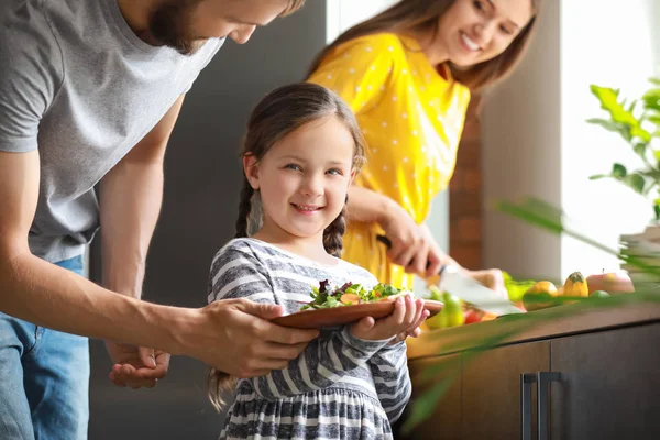 Little girl with parents preparing vegetable salad in kitchen — Stock Photo, Image