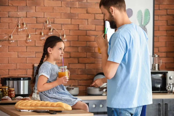 Молодой отец с дочкой пьют сок на кухне — стоковое фото