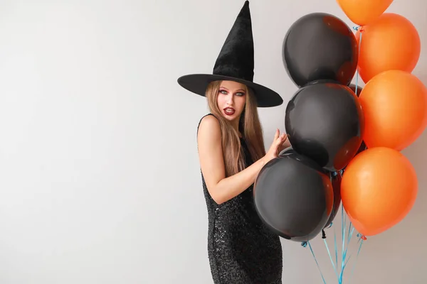 Mooie vrouw verkleed als heks voor Halloween op lichte achtergrond — Stockfoto