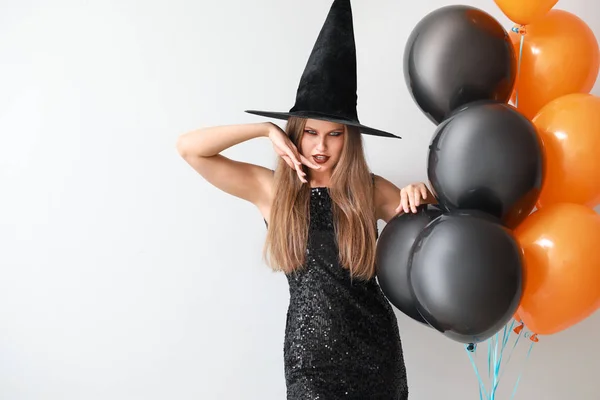 Mooie vrouw verkleed als heks voor Halloween op lichte achtergrond — Stockfoto