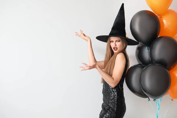 Mooie vrouw verkleed als heks voor Halloween op lichte achtergrond — Stockfoto