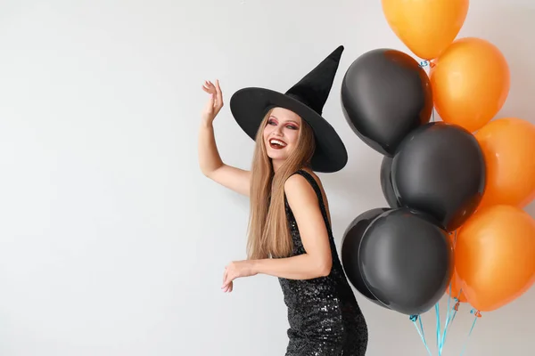 Mooie vrouw verkleed als heks voor Halloween op lichte achtergrond — Stockfoto