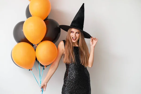 Beautiful woman dressed as witch for Halloween on light background — Stock Photo, Image