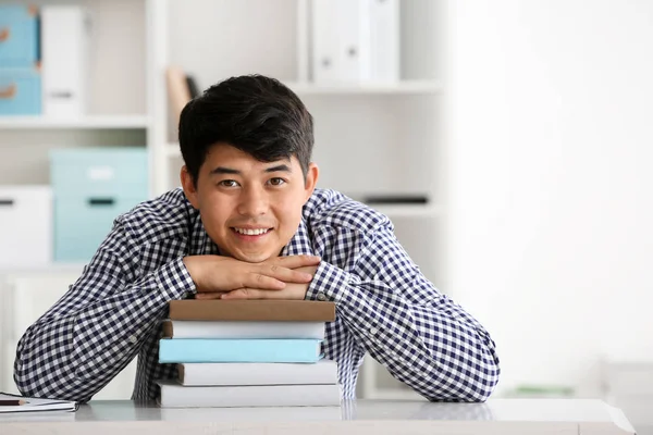 テーブルに座っている本を持つアジアの学生 — ストック写真