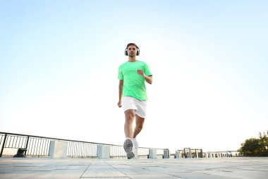 Yakışıklı sportif adam müzik dinlerken ve açık havada çalışan
