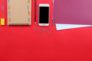 Renkli arka planda kırtasiye ile modern cep telefonu