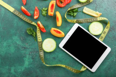 Taze meyve, sebze ve renkli arka planda ölçüm bandı ile modern tablet bilgisayar