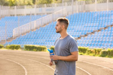 Stadyumda su şişesi ile sportif adam