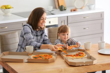 Mutlu anne ve küçük kızı evde pizza yiyor
