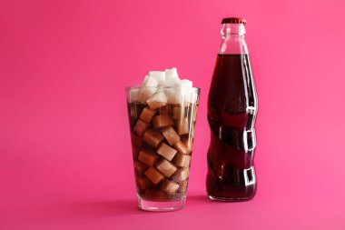 Renkli arka planda şeker küpleri ile şişe ve kola cam