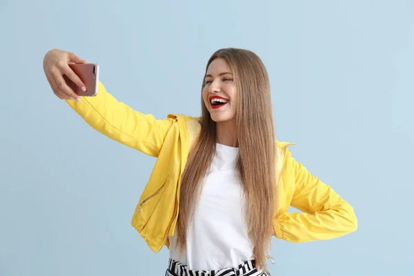 Glückliche junge Frau macht Selfie auf farbigem Hintergrund — Stockfoto