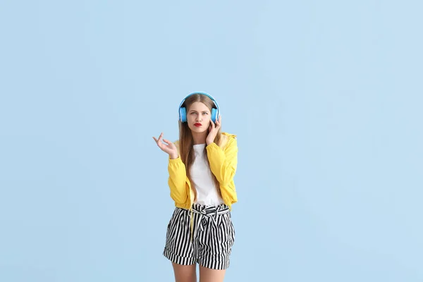 Doordachte jonge vrouw luisteren naar muziek op kleur achtergrond — Stockfoto