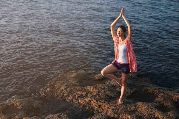 Young woman practicing yoga near river — Stock Photo, Image