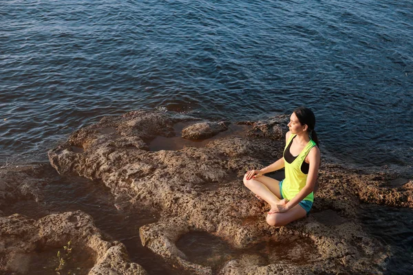 Young woman meditating near river — Stock Photo, Image