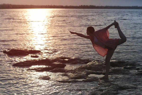 Young woman practicing yoga near river in morning — Stock Photo, Image
