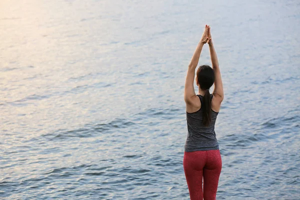 Young woman practicing yoga near river — Stock Photo, Image