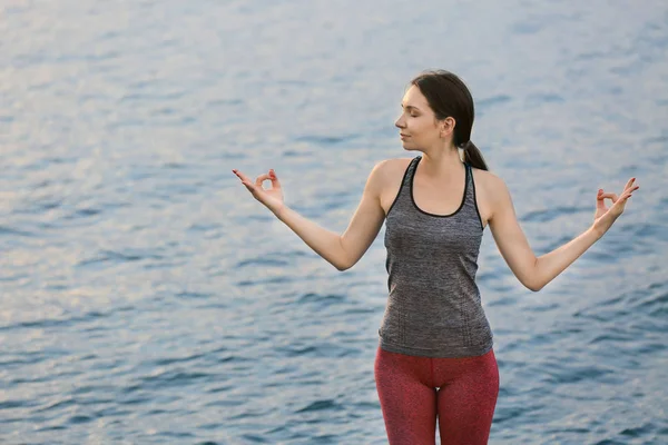 Young woman practicing yoga near river — Stock Photo, Image