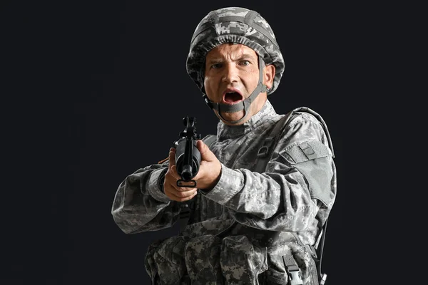 Maturo maschio soldato mira da assalto fucile su sfondo scuro — Foto Stock