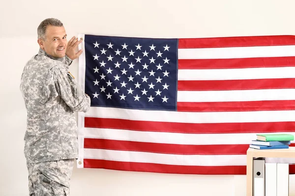 Mature male soldier hanging USA flag on wall in headquarters building — Stock Photo, Image