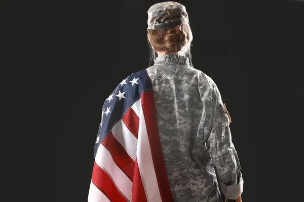 Young female soldier with USA flag on dark background, back view — Stock Photo, Image