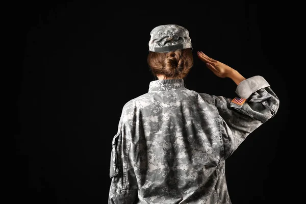 Saluting female soldier on dark background, back view — Stock Photo, Image