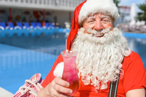 Santa Claus with cocktail near swimming pool at resort — Stock Photo, Image
