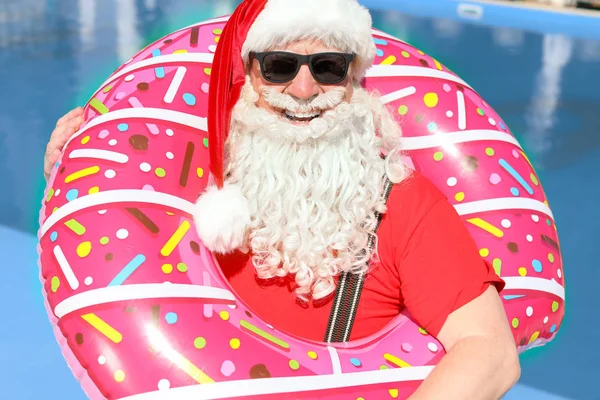 Santa Claus with inflatable ring near swimming pool at resort — Stock Photo, Image